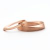 Two gold wedding bands, one is a twisted band and the other is a simple band.