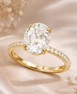 3 carat oval lab grown diamond engagement ring in yellow gold with pavé diamond band on soft beige background